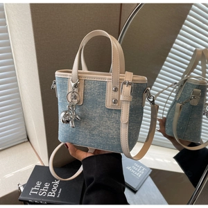 Detail of blue denim bucket bag featuring cream leather trim and silver balloon dog charm