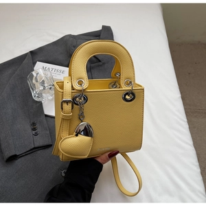 Close-up of yellow litchi pattern leather handbag with heart charm and round handle