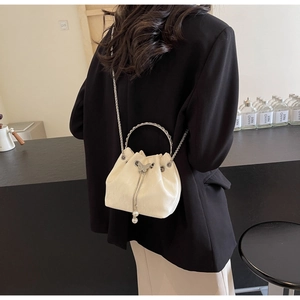Vue arrière d'un mannequin portant un sac seau blanc avec breloques papillon et perle