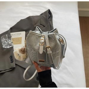 Detail of silver snakeskin textured bucket bag with gold hardware and plush charm