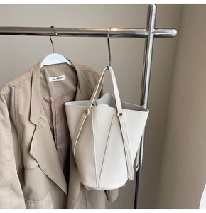 Detailed view of white litchi grain leather bucket bag with V-shaped stitching design