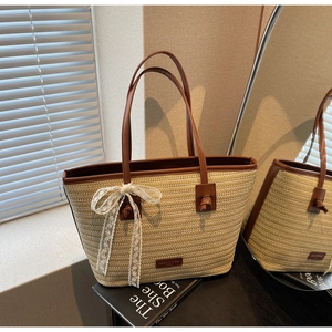 Détail d'un sac cabas en paille tissée avec bordure en cuir brun et nœud en dentelle