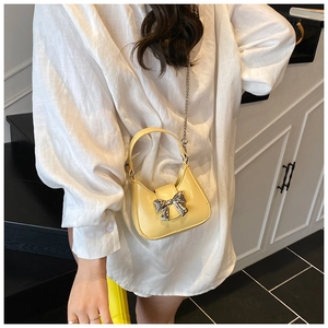 Détail du sac demi-lune jaune clair avec nœud en métal argenté et bandoulière chaîne