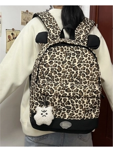 Close-up of leopard print backpack featuring cute black bear ears and a plush white bear charm