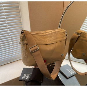 Detail view of khaki nylon crossbody bag with multiple zippers and wide strap via mirror reflex