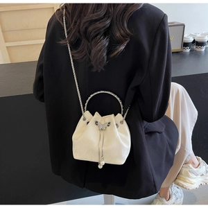 Détail du sac seau crème avec poignée en anneau argenté et breloques papillon perle