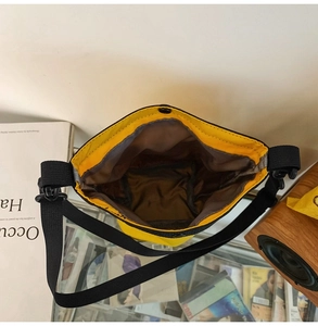 Vista dettagliata della borsa a tracolla in nylon giallo con bordo nero e fodera