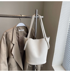 Close-up of litchi grain cream bucket bag with thin shoulder straps and rivet detail