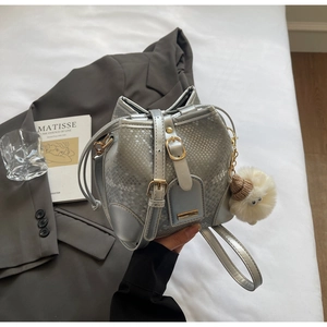Detail of silver snake-pattern bucket bag with gold hardware and plush charm