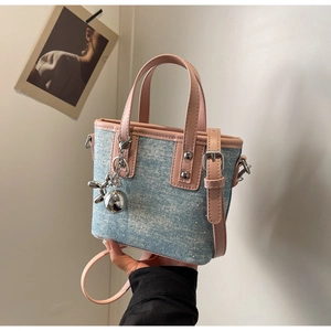 Detail of blue denim mini bucket bag with pink leather trim and metal puppy charm