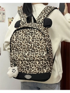Detail of leopard print backpack with cute ears and a plush bear charm on white background