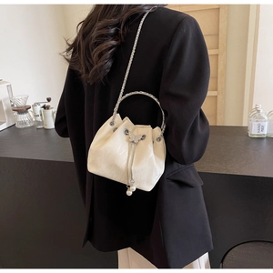Détail du sac seau blanc plissé avec poignée anneau métal et breloques de perles