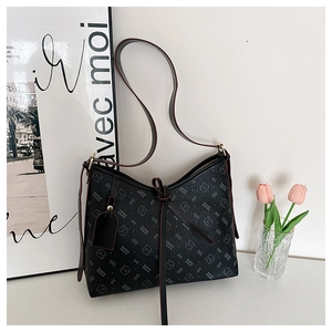 Detail of black pebbled faux leather bag featuring bear prints and a decorative bow tie