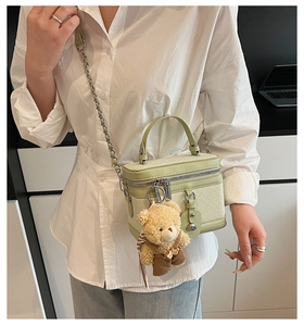 Détail du sac bandoulière tissé vert clair avec un adorable ours en peluche marron