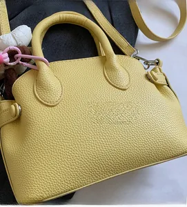 Detail of yellow lychee pattern shell bag with metal rings and plush animal charm