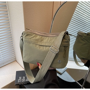 Detail of olive green nylon crossbody bag showing multiple zipper compartments and wide strap