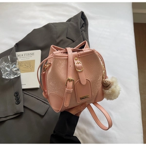 Detail of pink snakeskin bucket bag with gold hardware and plush pompom on a blazer