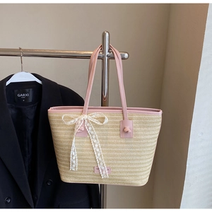 Détail du sac cabas en paille avec bandoulières en cuir rose et nœud en dentelle blanche