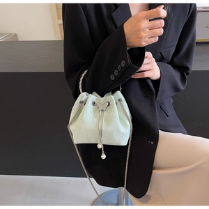 Détail du sac seau en satin vert menthe avec anse argentée, chaîne et breloque papillon