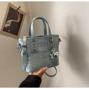 Detail of light blue denim bucket bag with silver studs and balloon dog charm