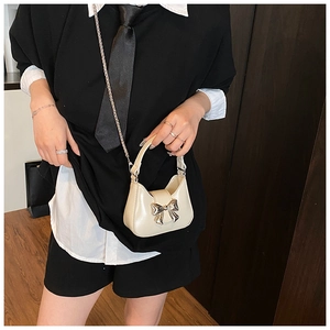 Détail du mini sac crème avec nœud en métal argenté et bandoulière en chaîne fine