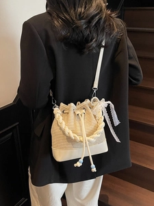 Fashionable beige woven bucket bag with white leather handle and pearl charm detail