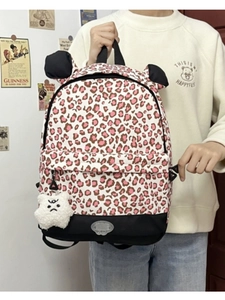 Detailed view of pink leopard print backpack featuring black cat ears and a plush charm