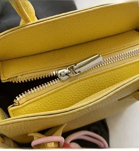 Close-up of smooth silver metal zipper on yellow lychee grain leather handbag detail