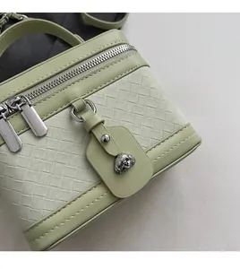 Détail du sac boîte vert clair montrant la texture tissée, les fermetures et le bijou