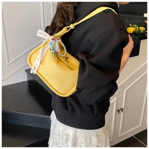 Detailansicht der gelben Lederhandtasche mit Spitzenschleife und Perlenketten-Träger