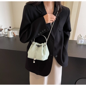 Détail du sac seau vert menthe avec motif embossé, anse en métal et breloque perle