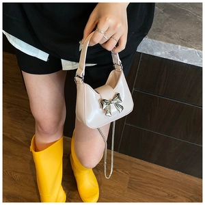 Détail du mini sac à main en cuir verni rose avec nœud argenté et bandoulière chaîne