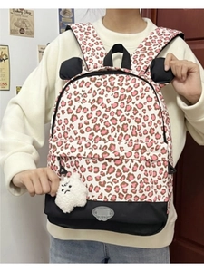 Pink leopard print backpack with cat ears and white plush toy shown on person