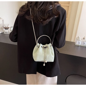 Détail du sac seau vert clair avec poignée argentée et breloque papillon perlé