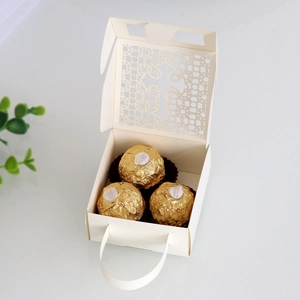 Detailed laser-cut hollow cross design on ivory wedding candy gift box with handle