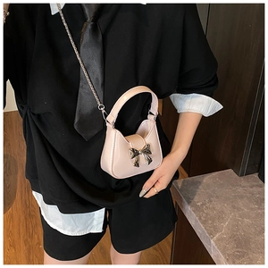 Gros plan du mini sac rose à chaîne avec fermoir nœud argenté sur cuir lisse brillant