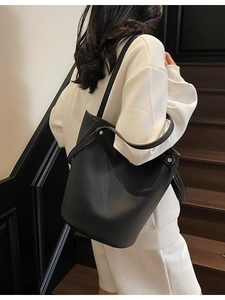 Minimalist black pebble leather bucket bag with top handle and metallic studs decoration