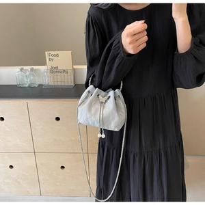 Détails du sac seau gris clair avec fermoir papillon argenté et finitions en perles