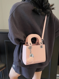 Pink lychee leather handbag with silver heart charm and classic top handles in a lifestyle view