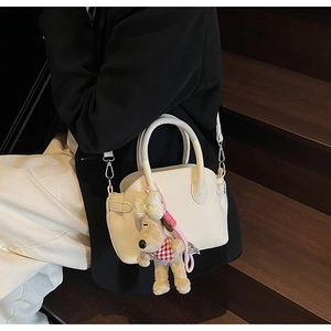 Bolso bandolera beige con colgante de perrito de peluche llevado por modelo