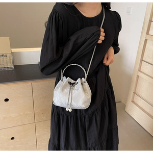 Détail du sac seau nacré avec bandoulière chaîne argentée et breloque papillon noir