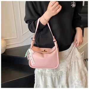 Detail of pink pebbled leather crossbody bag with gold lock and lace accessory
