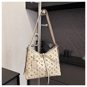 Close-up of beige shoulder bag with pebble texture and bear pattern on a metal stand