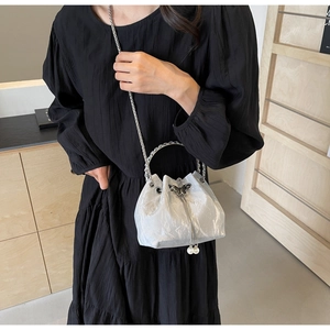 Détail du sac seau argenté avec fermoir papillon, perles et bandoulière chaîne
