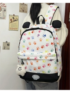 Detail showing the bottom reflective patch and side plush charm of a leopard print backpack