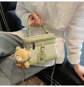 Détail du sac bowling tissé vert clair avec chaîne argentée et pendentif ours en peluche