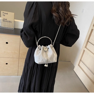 Détail du sac seau argenté texturé avec papillon en métal et glands en perles blanches