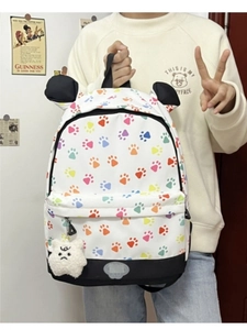 Detail of white canvas backpack with paw prints and plush bear pendant detail