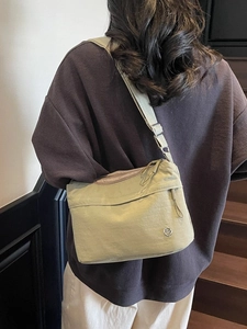 Olive green nylon crossbody tote bag with multi-layer zippers worn by a model