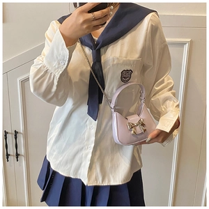 Mini sac hobo lavande avec nœud doré porté sur un uniforme d'écolière
